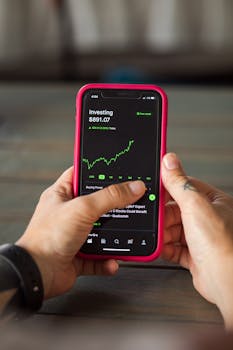 Close-up of hands holding a smartphone displaying stock market investment app.